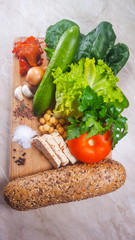 Salad, vegetables, tofu, spices and bread with seeds on a cutting board