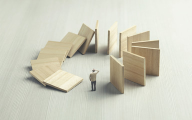 man looking at dominoes collapsing around him