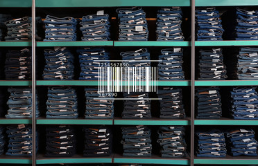 Barcode and collection of stylish jeans on shelves in wholesale shop