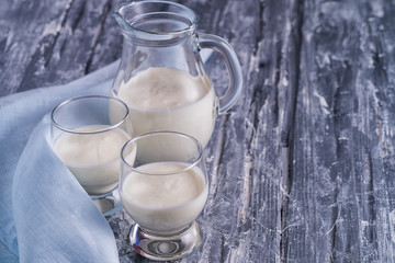 fermented drink kefir in a jug and glass glasses filled with kefir on gray background.
