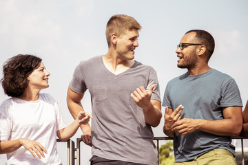 Fototapeta premium Multiracial people talking outdoors. Young multiethnic men and woman standing together and talking on street. Communication concept