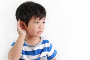 Portrait of little Asian boy with hand by ear against white background.