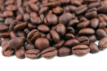 Dark coffee beans placed on a white scene.