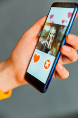 Online dating app in smartphone. Person swiping and liking profiles on relationship site or application. Single guy searching for love partner.