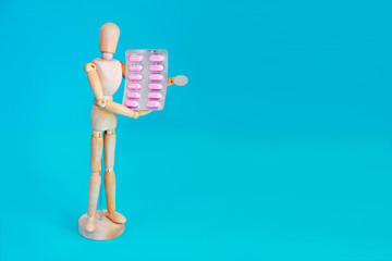 wooden yellow mannequin holds pink medical pills