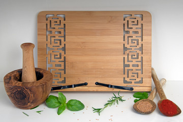 Wooden recipe book stand with mortar and pestle, herb leaves and dried spices
