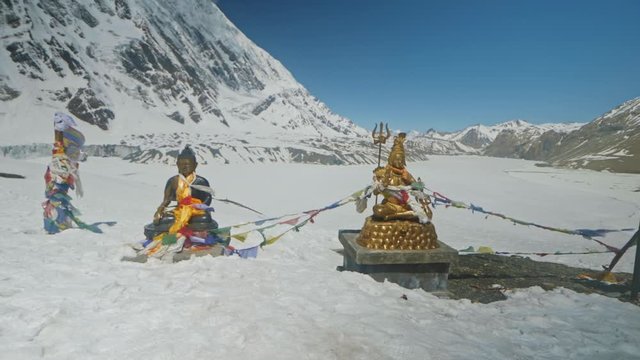 Statue of Bouddha and Shiva shining in snow highlands against clear blue sky