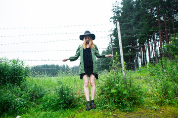 young pretty blond woman in hipster hat posing in fashion dress outside in green country rancho, lifestyle people concept