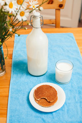 Simply stylish wooden kitchen with bottle of milk and glass on table, summer flowers camomile, healthy foog moring concept