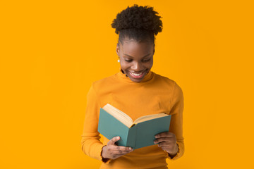 beautiful young african woman on yellow background with a book