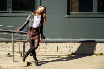 Spring photo of a happy smiling beautiful girl with emotions in the sun outdoors on the background of the steps in the city. Model posing with hands in front of the camera.