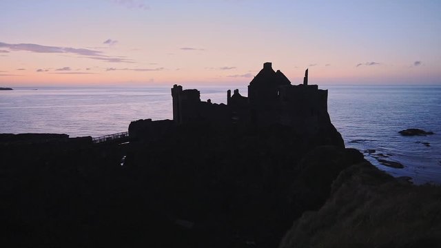 The Profile Of Dunluce Castle And The Coast Of Antrim And Glens During Sunset In Antrim County, Northern Ireland. -wide shot
