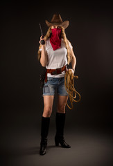 Studio portrait of a girl in a cowboy hat, with a red bandana, a gun and a rope