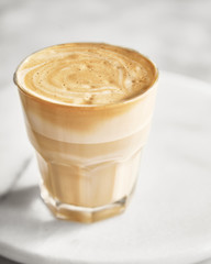 Dalgona coffee In a transparent glass on a marble background