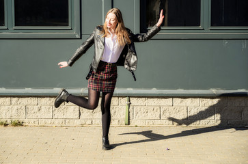 Pretty model posing jokingly in front of the camera. Spring photo of a happy smiling beautiful girl with emotions in the sun outdoors on the background of the steps in the city.