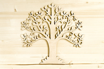 Laser cut wood tree ornament on wooden background.  Wooden tree symbol on wood texture with copy space..