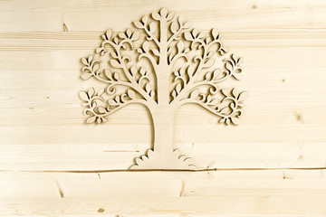 Laser cut wood tree ornament on wooden background.  Wooden tree symbol on wood texture with copy space..