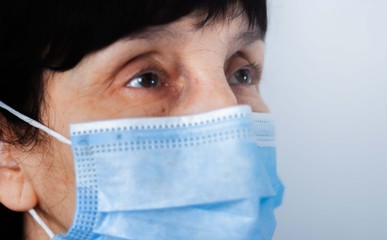 Coronavirus quarantine and Air pollution pm2.5 concept. Face of old sick woman wearing blue respirator mask for protect. Wuhan, China epidemic virus symptoms background.