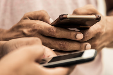 Cropped shot of young people using smartphones. Closeup shot of hands texting on modern phones....