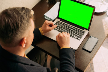 gray-haired male businessman working on a laptop. green screen