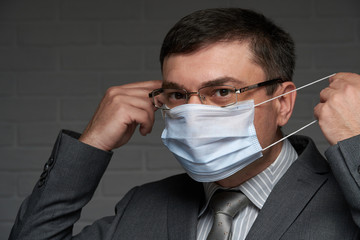 a man puts a mask on his face for antivirus individual protection - healthcare and medicine...