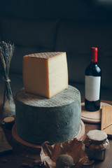 Composition with cheese and wine on a dark background. Slices of cheese and a glass of wine. Large round hard Parmesan cheese.