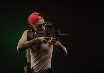 an athletic guy with a tattoo poses with a shotgun