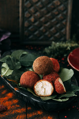 Balls of goat cheese in red pepper. Homemade natural hard cheese on a plate. Farm diet products.