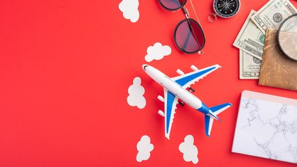 Travel and vacation. Red background, summer mood. Airplane, compass and passport with money. With space for design. Agency tour