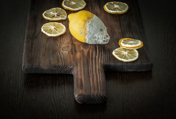 Fototapeta premium Old rotten lemon with dry slices on wooden board