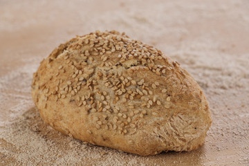 Traditionell gebackenes Sesam-Brötchen in Bäckerei auf mehligem Brett