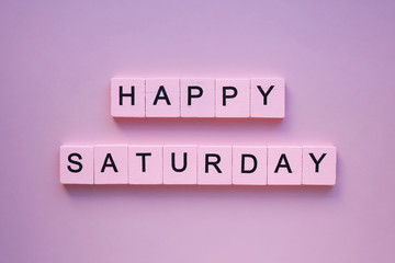 Happy saturday words wooden cubes on a pink background