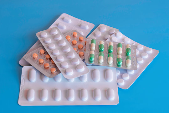 Seven blisters of generic tablets on blue background.Various pills in packages.No people and copy space.Stockpiling medications.Healthcare and medical.Social issue.Prescription medications. 
