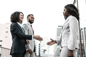 Diverse businesspeople meeting near office building. Business man and women standing in city street and giving hands for handshake. Business meeting concept