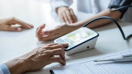 Fototapeta premium Doctor measuring patient blood pressure in clinic or hospital office. Medical and Health concept.