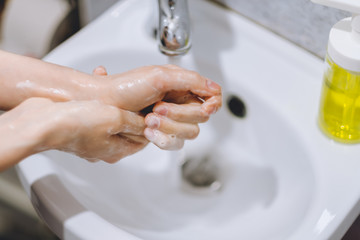 Woman washes hands with liquid soap at home in the bathroom