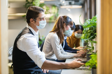 business man and woman wearing medical mask prevent dust and virus in the air, and using working online with smartphone in cafe.