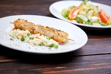 chicken kebab with rice and vegetables on the wooden background