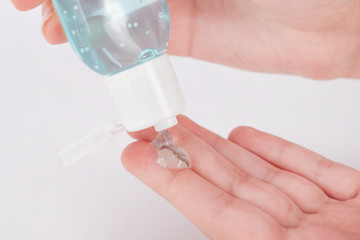 Antiseptic gel in  bottle spilling out onto fingers.Close up.Soft focus.Hands holding a blue vial.Concept of health protection,hands disinfection,prevention of virus and bacterial infections.