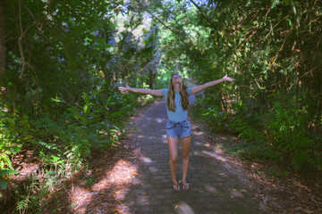 A beautiful and emotional girl rejoices among the tropical and exotic forest or jungle on the island of Bali. She shows her different emotions with tanned skin and glasses.