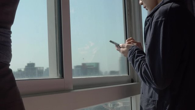 Man using phone and standing by the window