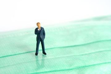 Obraz premium Miniature people photography - a businessman stands above green face mask