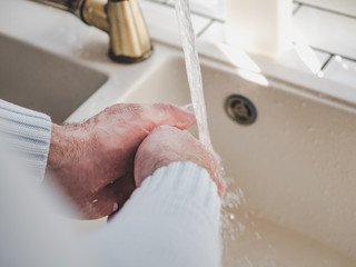 Fototapeta premium Men's hands and a bar of soap on a background of a vintage tap. Top view, closeup. Health Care and Prevention Concept
