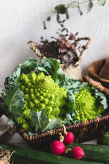 Assortment of seasonal vegetables and two romanescu cabbages in a basket