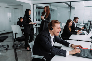 Side view of Smiling Coworkers sitting at a table with headphones. call center