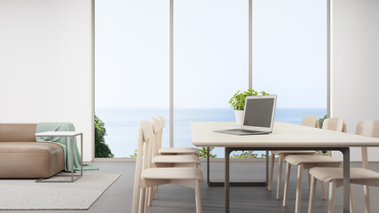 Laptop on table near living room in work from home and social distancing concept. 3d rendering of beach house interior with sea view.