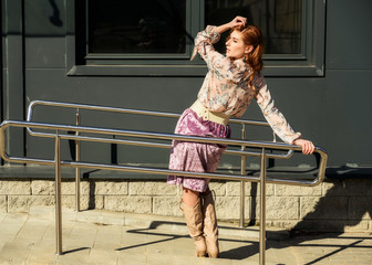 Full-length photo in bright weather of a fashionable glamorous beautiful woman with long hair on the background of the steps of the building in the spring in the sun.