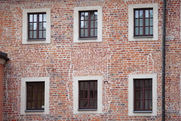Fototapeta na wymiar The facade of an old brick building with windows or cornices. Old brick walls