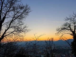 Fototapeta na wymiar Sunset at the Schlossberg in Graz with a view of the west of Graz as well as mountains and trees