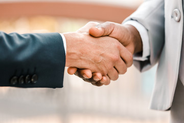Closeup of business leaders handshake. Business people in office suits shaking hands with each other. Formal communication concept